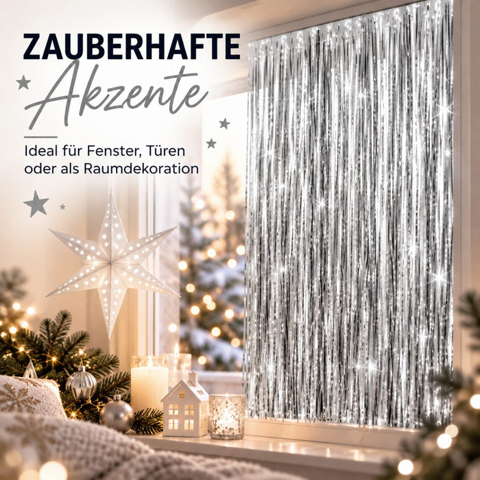 Silberner Lametta-Vorhang am Fenster, weihnachtlich dekoriert mit Sternlampe, Kerzen, Kugeln und Tannenzweigen.
